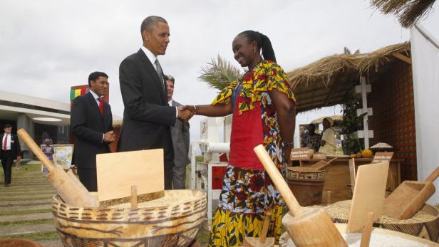 Barack Obama schüttelt einer Frau in traditioneller Kleidung die Hand.
