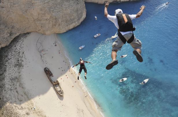 Zwei Fallschirmspringer springen über den Strand von Navagio mit einem Schiffswrack.