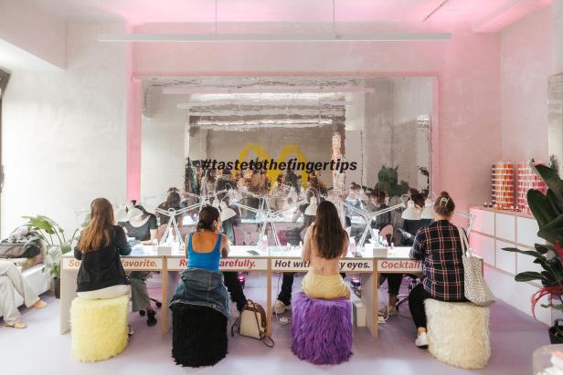 Kundinnen sitzen in einem Nagelstudio mit dem Hashtag #tastetothefingertips.