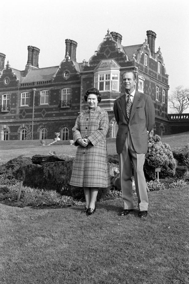 Königin Elisabeth II. und Prinz Philip posieren vor einem großen Gebäude.