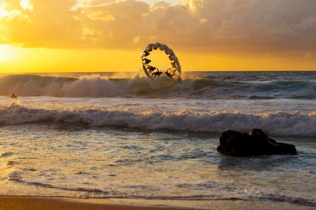 Eine Skulptur am Strand zeigt stilisierte Figuren im Sonnenuntergang.