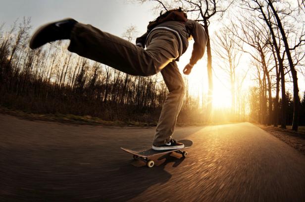 Ein Skateboardfahrer fährt auf einer Straße in Richtung Sonnenuntergang.