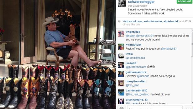 Arnold Schwarzenegger sitzt mit Cowboyhut und Zigarre vor seiner Sammlung von Cowboystiefeln.