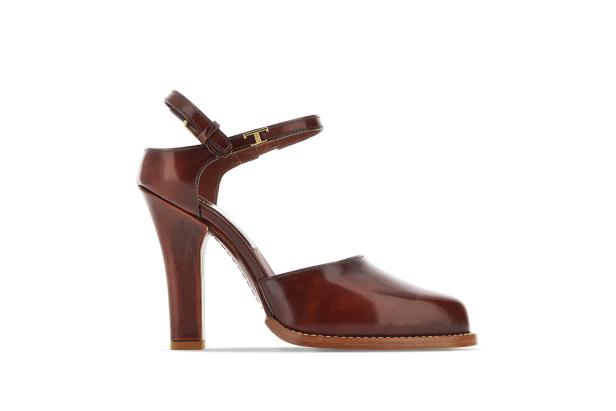Ein brauner Ledersandalen-Pumps mit hohem Absatz und Knöchelriemen steht auf einem weißen Hintergrund.