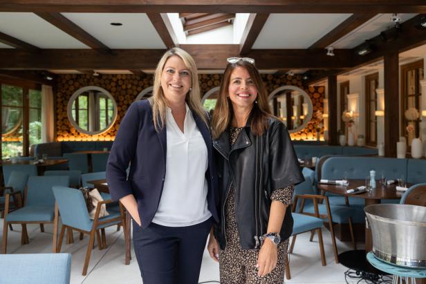 Zwei Frauen stehen in einem eleganten Restaurant nebeneinander.