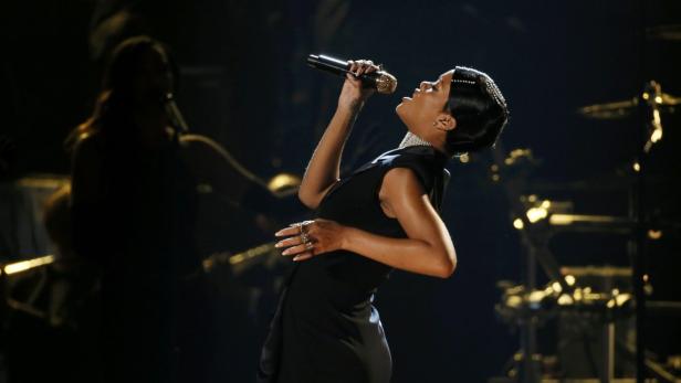 Rihanna singt während einer Aufführung in einem schwarzen Kleid.