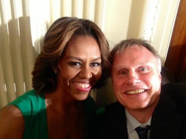 Michelle Obama posiert für ein Selfie mit einem Mann im Anzug.