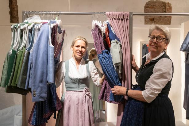 Zwei Frauen stehen in einem Geschäft vor einer Kleiderstange mit Dirndln.