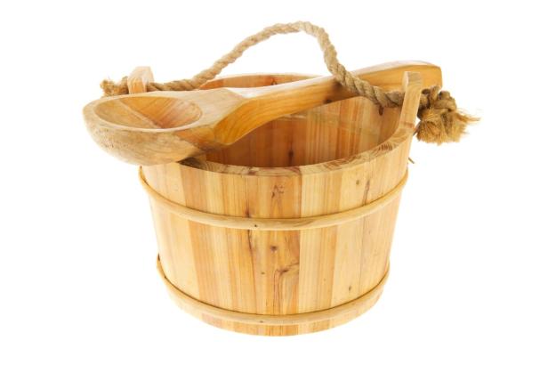 Ein hölzerner Eimer mit einem Schöpflöffel liegt darauf.