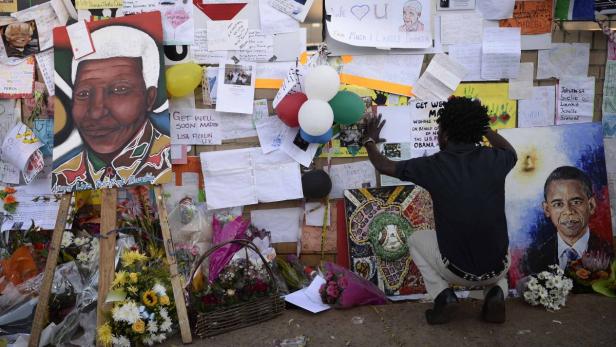 Eine Gedenkstätte mit Porträts von Nelson Mandela und Barack Obama, Blumen und Botschaften.