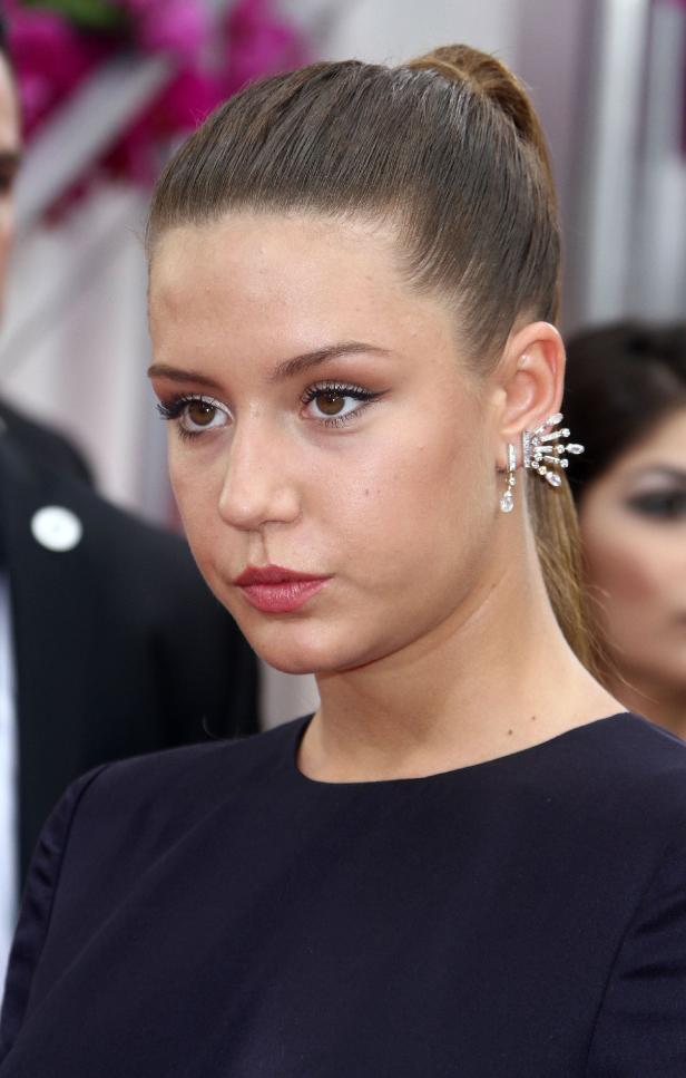 Nahaufnahme einer jungen Frau mit hochgesteckten Haaren und auffälligen Ohrringen.