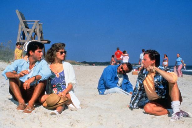 Mehrere Personen sitzen am Strand unter blauem Himmel.