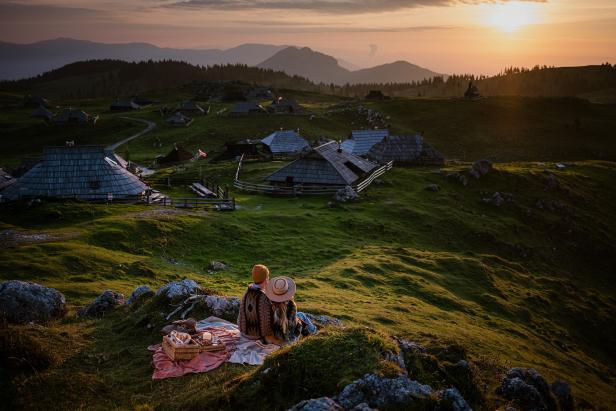 Ein Paar genießt den Sonnenuntergang mit Picknick auf der Velika Planina.