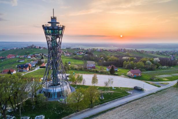 Ein Aussichtsturm überblickt eine ländliche Gegend bei Sonnenuntergang.