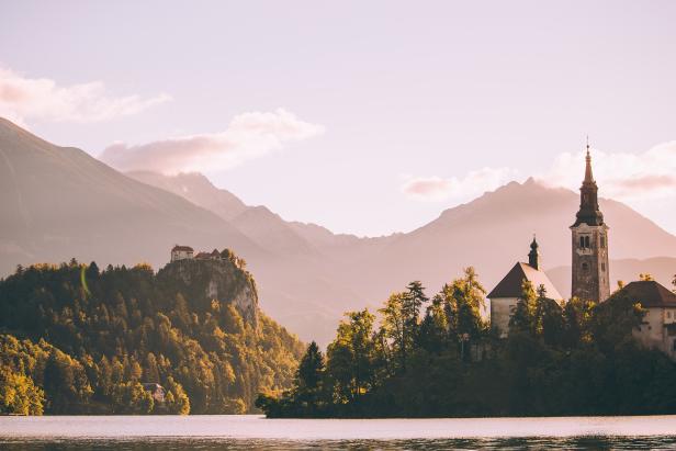 Der Bleder See mit der Kirche auf der Insel und der Burg auf dem Felsen im Hintergrund.