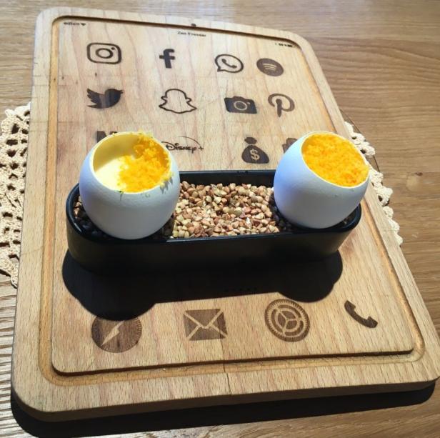 Gebeiztes Ei mit Spinat, Erdäpfelstroh und Espuma, serviert auf einem einem iPad nachempfundenen Holzbrett