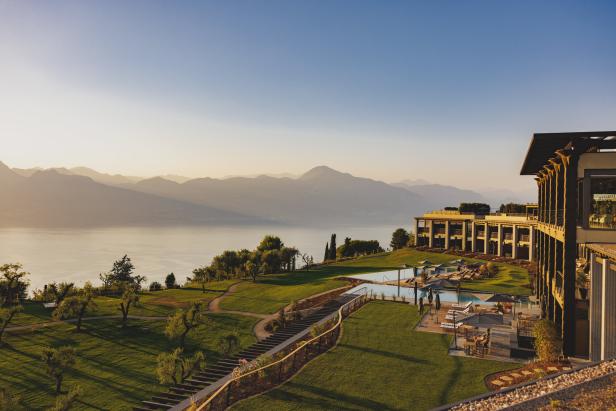 Ein Hotelresort mit Pool und Blick auf einen See und Berge im Hintergrund.