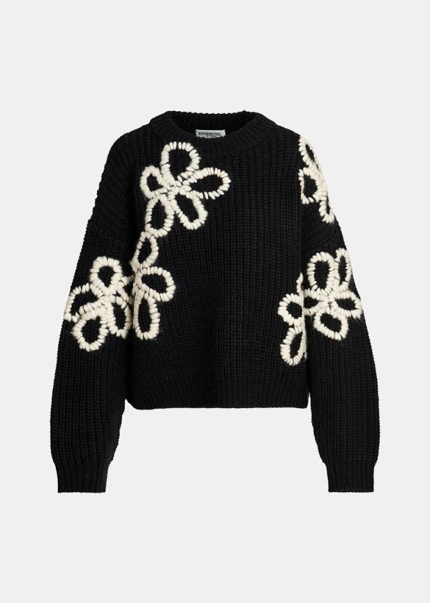 Ein schwarzer Strickpullover mit aufgenähten, weißen Blumen.