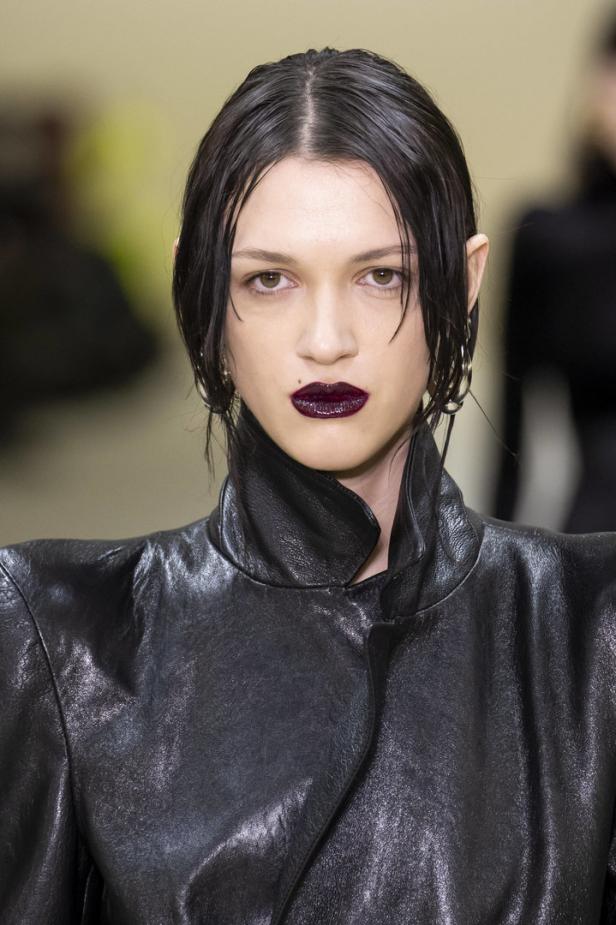 Eine Frau mit dunklem Lippenstift und einem schwarzen Lederjackett.