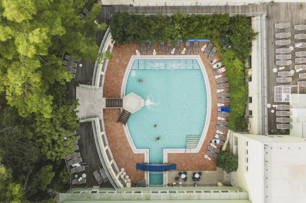 Luftaufnahme eines Schwimmbads mit Badegästen und Liegestühlen.