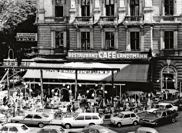 Das Café Landtmann in Wien mit Gästen im Freien und geparkten Autos davor.
