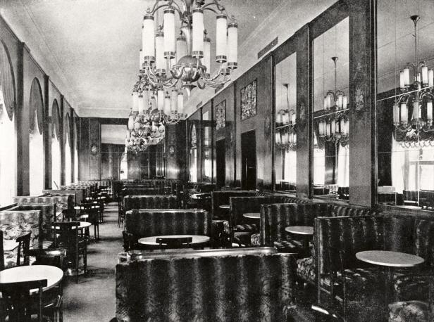 Das Innere eines eleganten, leeren Cafés mit vielen Tischen und gepolsterten Sitzbänken.