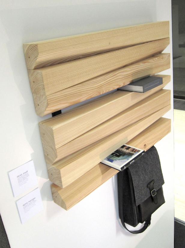 Ein Regal aus hellem Holz mit Büchern und einer Tasche an einer weißen Wand.