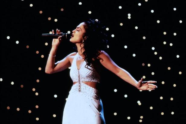 Jennifer Lopez singt in einem weißen Kleid auf einer Bühne mit Sternen im Hintergrund.