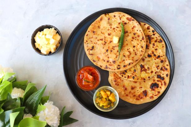 Paratha, ein indisches, hausgemachtes Gericht, serviert mit Butter und Pickles.