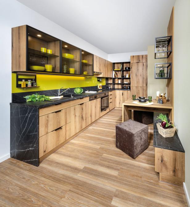 Eine moderne Küche mit Holzfronten, schwarzer Arbeitsplatte und gelbem Fliesenspiegel.