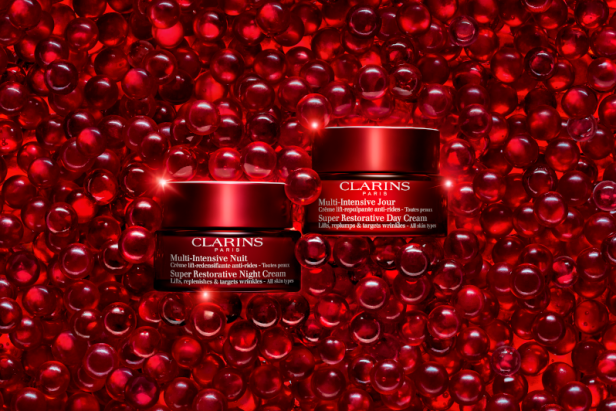 Zwei Tiegel Clarins Multi-Intensive Nacht- und Tagescreme auf einem Bett aus roten Perlen.