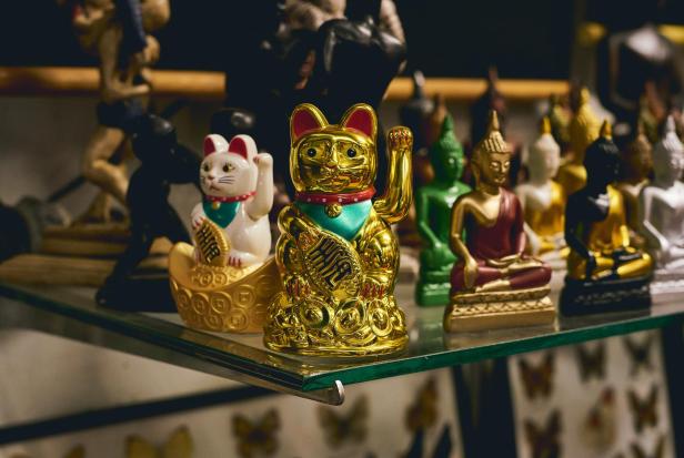 Goldene Winkekatze auf einem Glasregal.