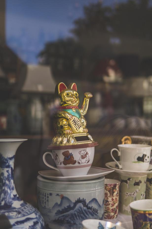 Goldene Glückskatze auf einer Tasse stehend.