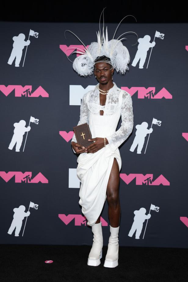 Lil Nas X auf den VMAs trägt weißes gerafftes Kleid mit großem Kopfschmuck und einer Bibel in der Hand.