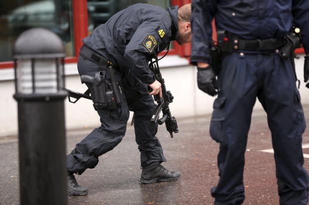 Ein Polizist mit einer Waffe in der Hand beugt sich nach unten.