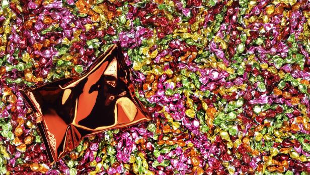 Viele bunte Süßigkeiten liegen nebeneinander, eine davon ist bereits geöffnet.