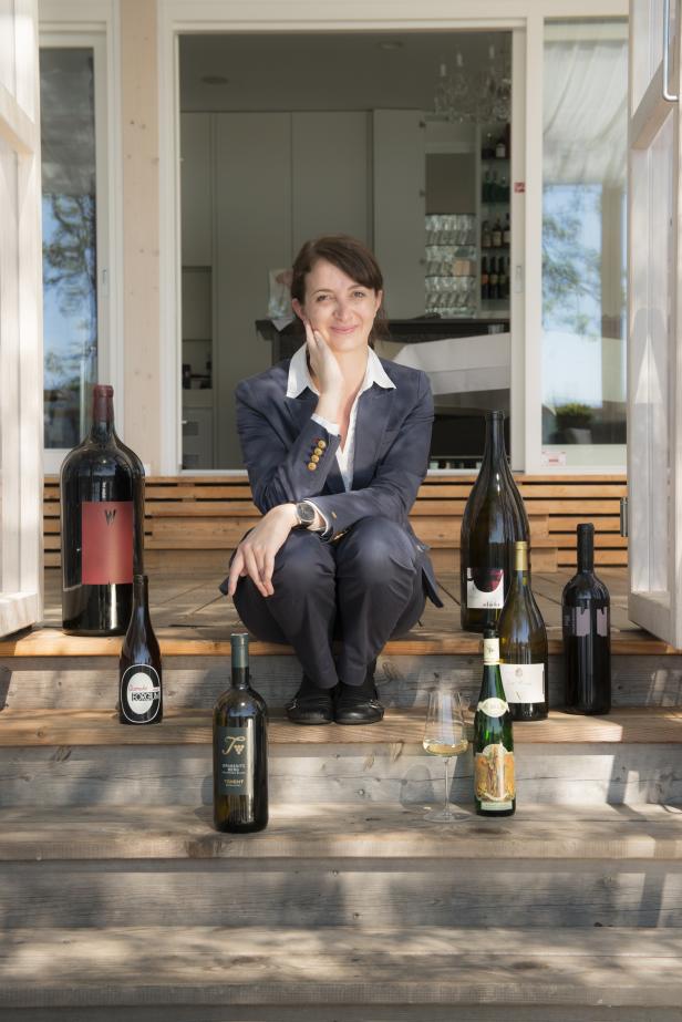 Eine Frau posiert auf einer Holztreppe mit mehreren Weinflaschen.