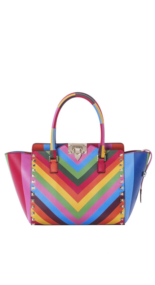 Eine Handtasche mit bunten, zickzackförmigen Streifen und silbernen Nieten.