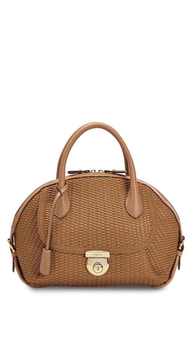 Eine gewebte, hellbraune Handtasche mit Ledergriffen und goldenem Verschluss.