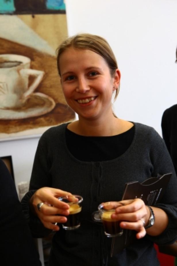 Eine lächelnde Frau hält zwei Gläser mit Espresso in den Händen.