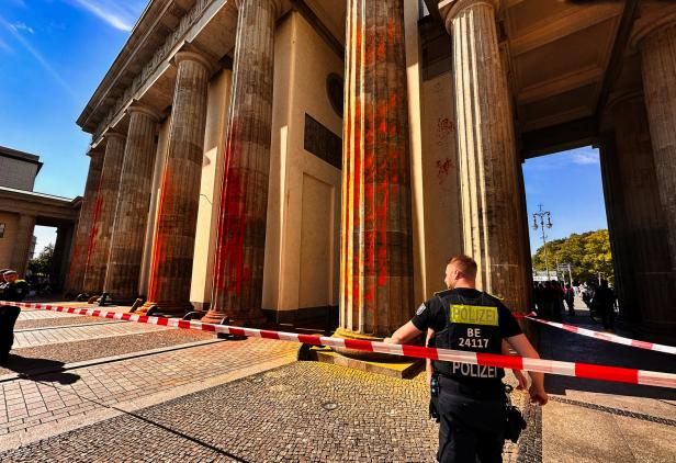 Das Brandenburger Tor in Berlin ist mit roter Farbe beschmiert und von einem Polizisten bewacht.