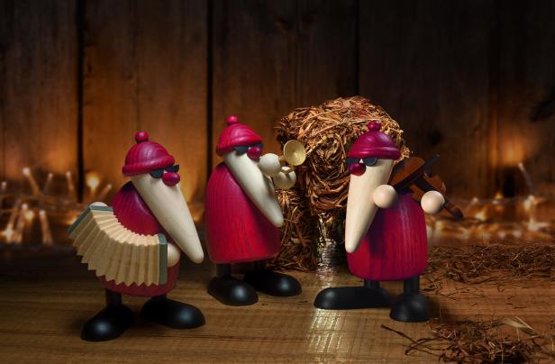 Drei hölzerne Weihnachtsmannfiguren spielen Akkordeon, Trompete und Geige.