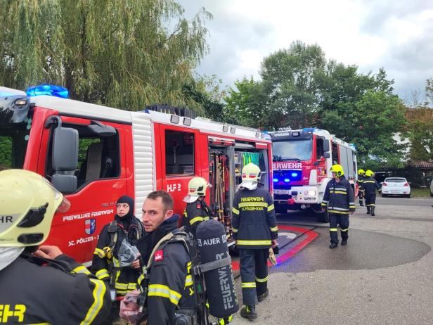Feuerwehrleute der Freiwilligen Feuerwehr St. Pölten-Stadt stehen vor ihren Einsatzfahrzeugen.