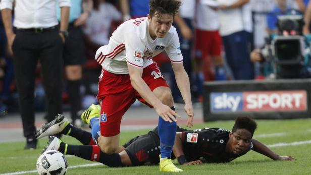 Ein Fußballspieler des Hamburger SV steht über einem am Boden liegenden Spieler.