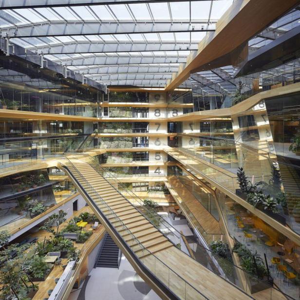 Blick in das Atrium des Booking.com Campus mit begrünten Wänden und hölzernen Treppen.