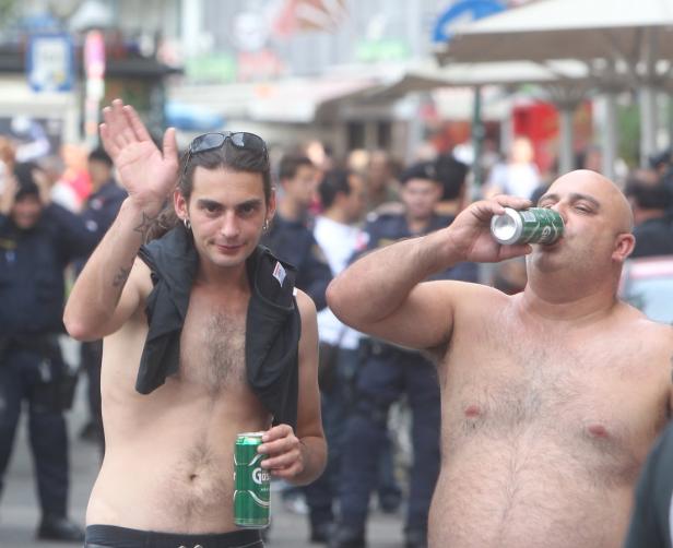 Zwei Männer ohne Hemd trinken Bier in einer Menschenmenge.
