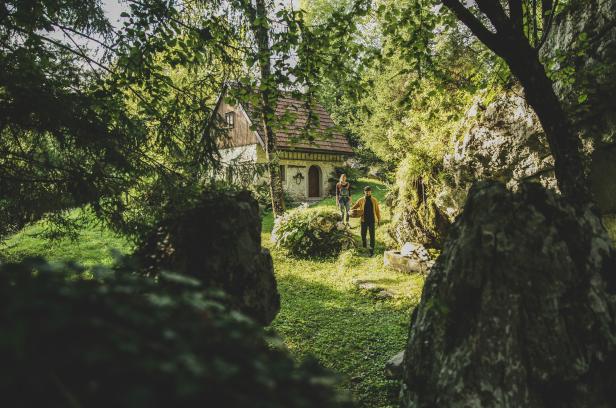 Ein Paar geht auf ein kleines Haus mit rotem Ziegeldach zu.