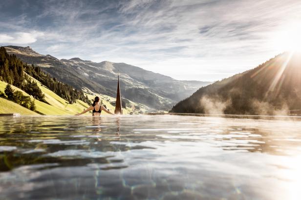 Eine Frau entspannt in einem Infinity-Pool mit Blick auf die Berge.