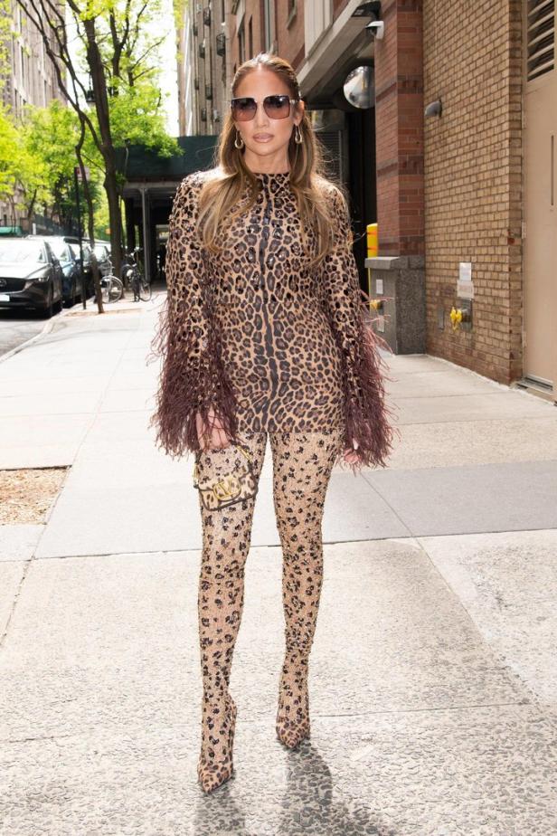 Jennifer Lopez trägt einen Leopardenmuster-Overall mit Federn an den Ärmeln und eine Valentino-Tasche.