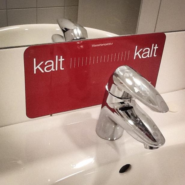 Ein Waschbecken mit einem Schild, das die Wassertemperatur als „kalt“ anzeigt.